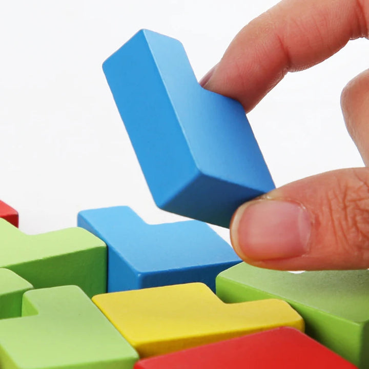 Hand holding a blue L-shaped wooden block above colorful puzzle pieces