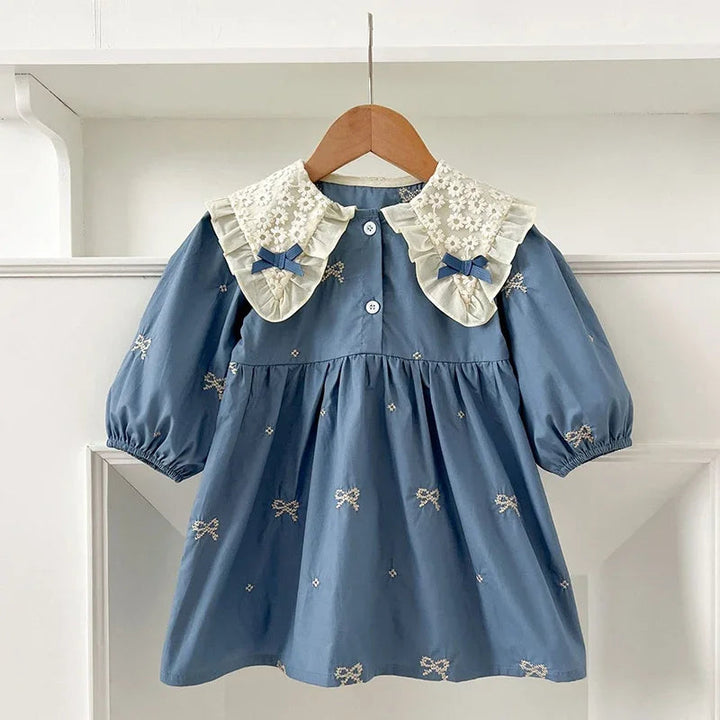 Blue A-line dress with a ruffled lace collar, matching bows, and gathered sleeves on a hanger