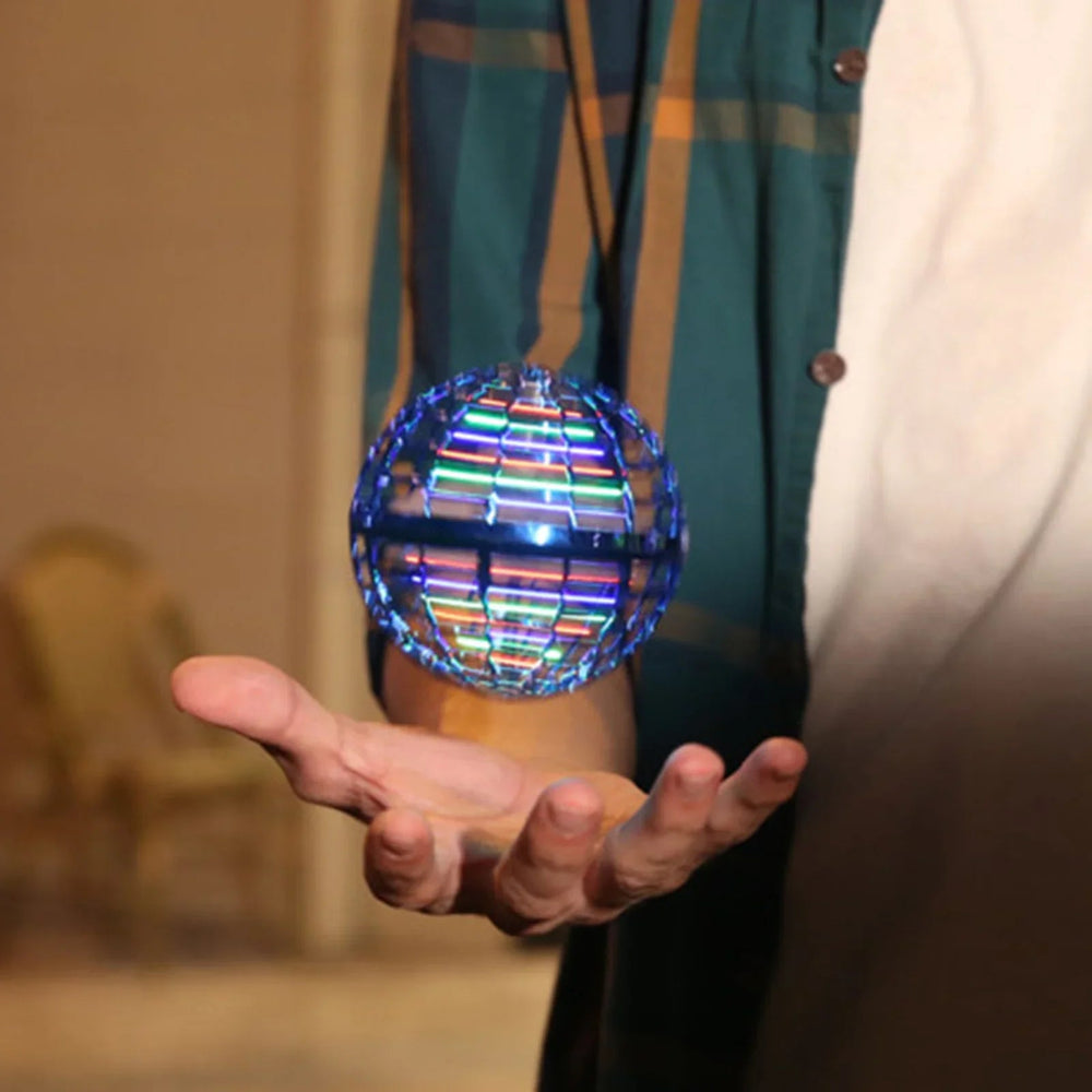 Illuminated blue flying ball hovering above an adult's open hand indoors