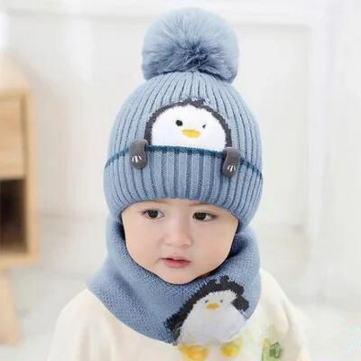 Child wearing a blue penguin pom-pom hat and matching scarf