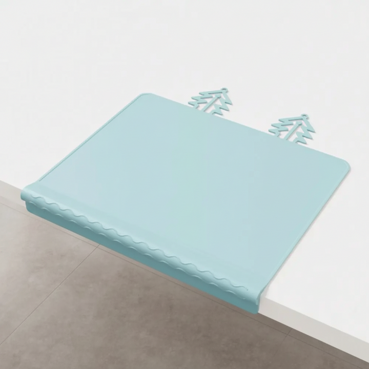 Blue silicone placemat with its front edge draped over a white table