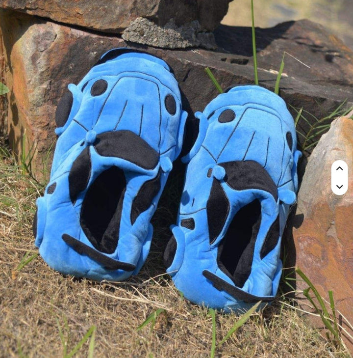 Blue racing car slippers beside rocks, showing dark interiors and stitched hood details