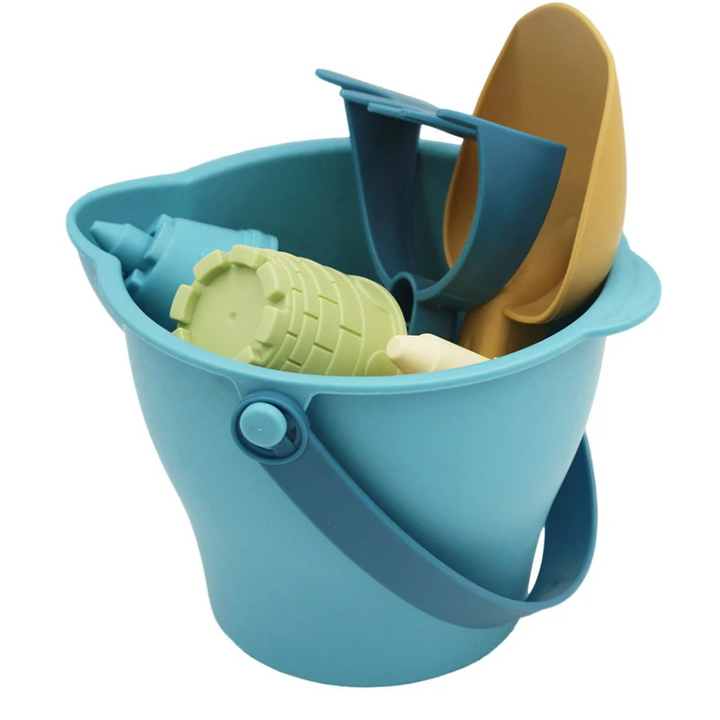 Blue pouring bucket holding a yellow scoop, blue rake, and sand molds