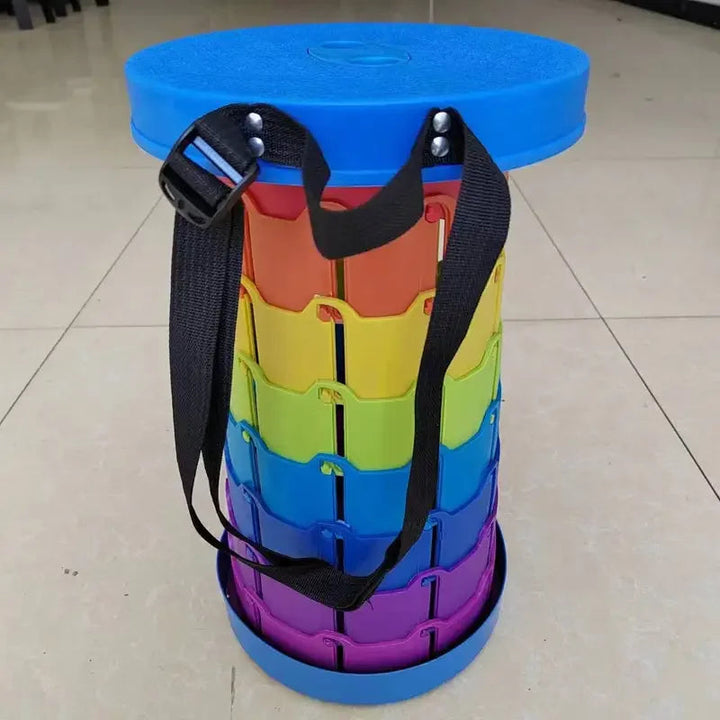 Blue-topped rainbow folding stool with a black carrying strap on a tiled floor