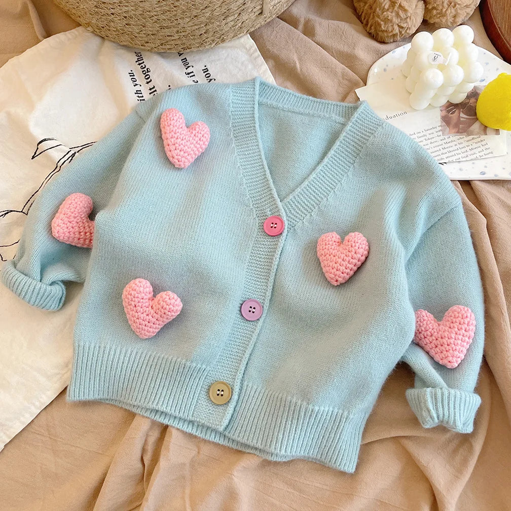 Blue heart cardigan laid flat, showing long sleeves, a V-neck, and button front