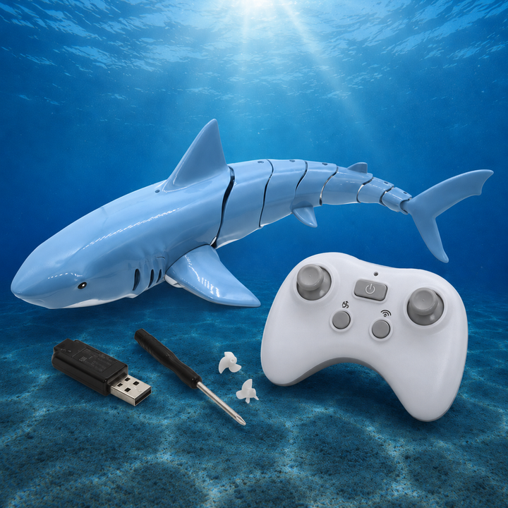 Blue RC shark beside its remote, USB charger, screwdriver and propellers