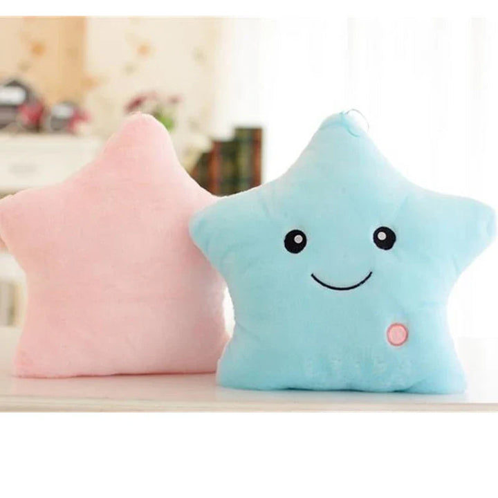 Front of a blue smiling star pillow beside the back of a pink star pillow