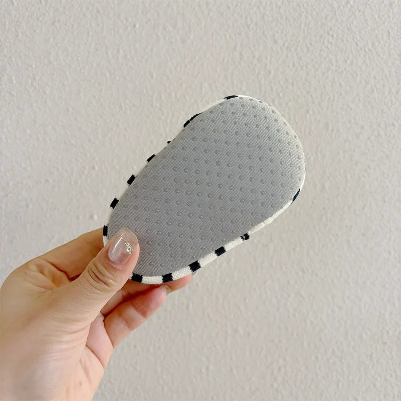 Close-up of the gray dotted sole on a blue-striped baby shoe