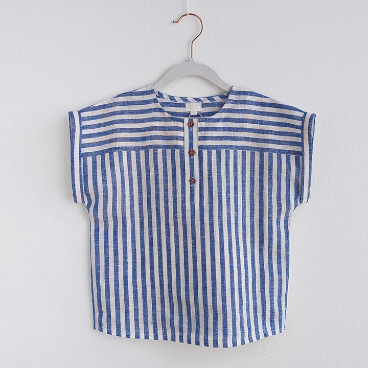Blue striped cotton-linen shirt hanging against a light wall