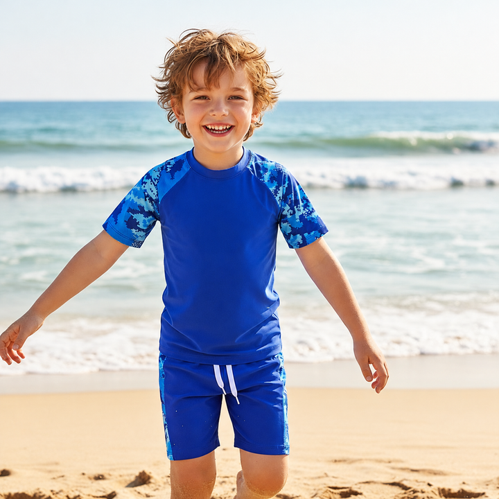 Child wearing a blue short-sleeve swim shirt and matching shorts at the beach