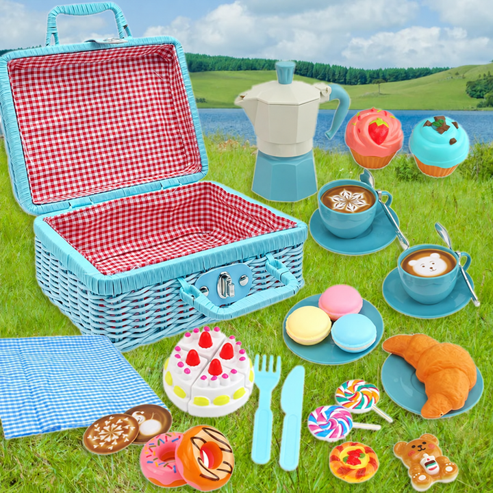 Blue tea party set arranged on grass with an open picnic basket, toy moka pot, cups, and pretend treats