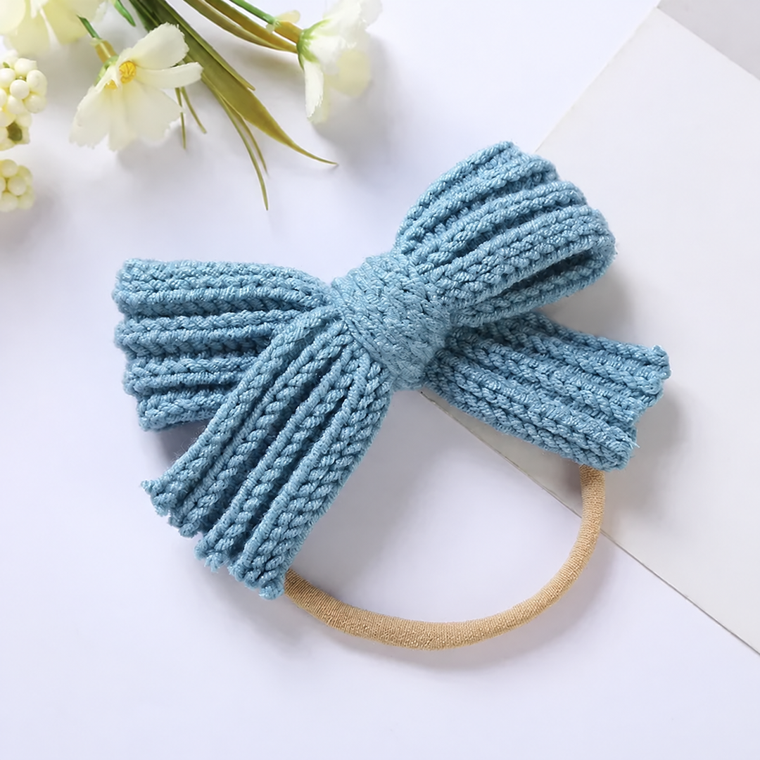 Blue knitted bow headband showing the ribbed texture and central knot