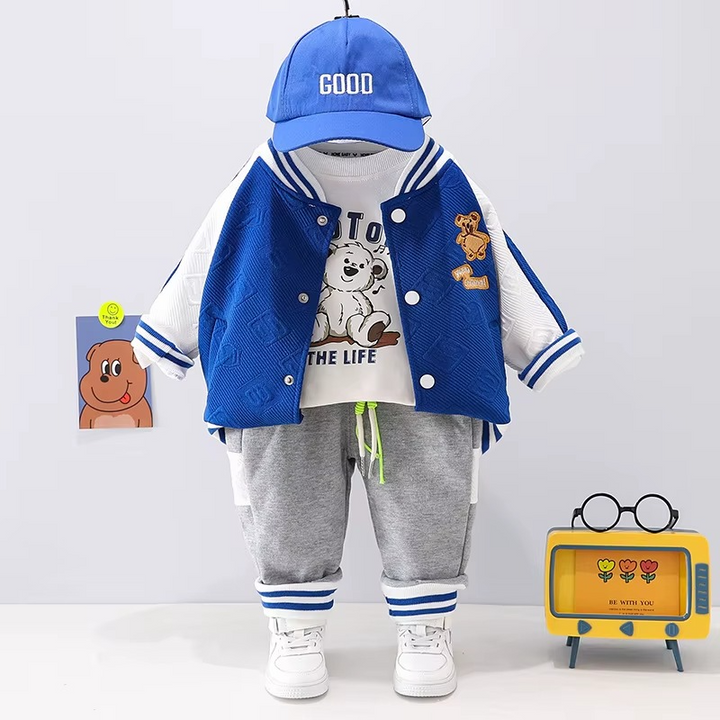 Blue-and-white varsity jacket, graphic T-shirt, and gray joggers displayed with a blue cap