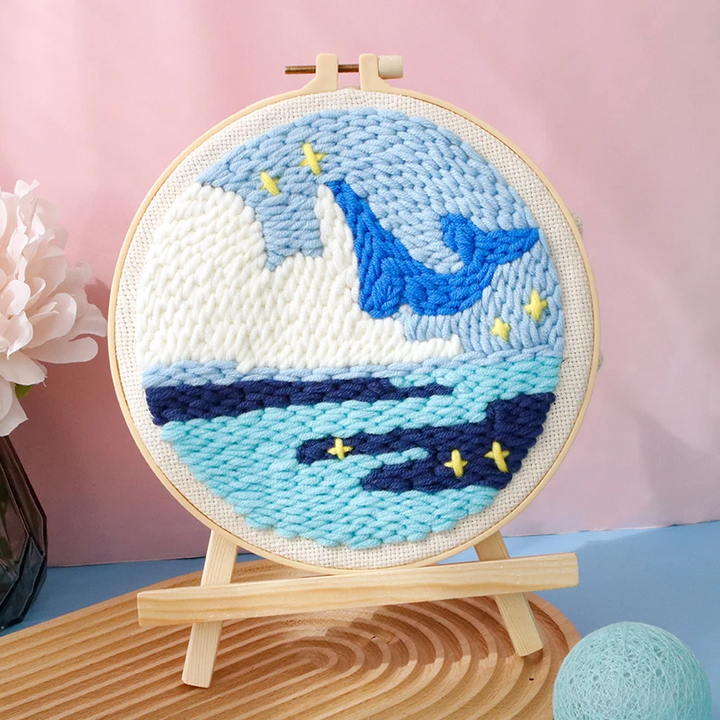Blue whale punch needle hoop with layered ocean waves and small yellow accents
