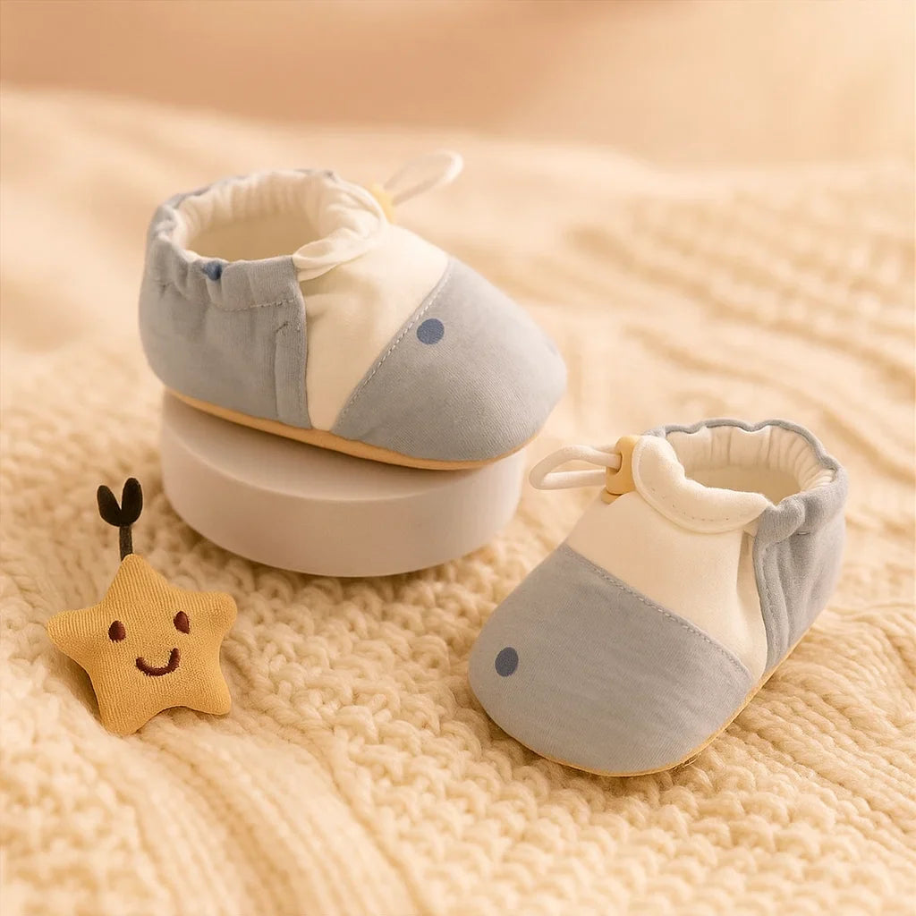 Pair of blue-and-white baby shoes with elastic openings on a cream knit blanket