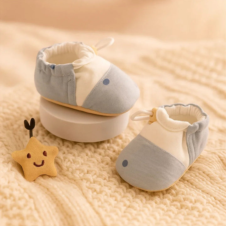 Pair of blue-and-white baby shoes with elastic openings on a cream knit blanket