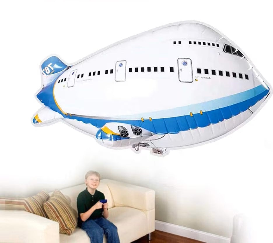 Blue-and-white airplane balloon floating above a child holding a remote control on a sofa