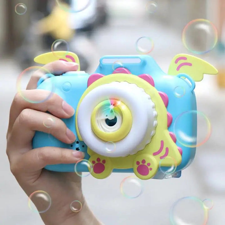 Hand holding a blue bubble camera with yellow wings as bubbles float around it.