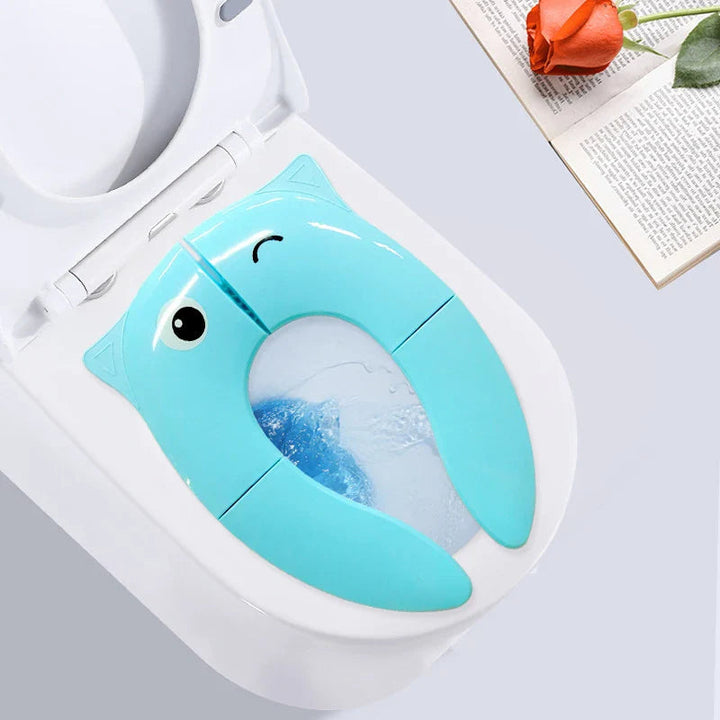 Blue toilet training seat with a winking animal face positioned on a toilet