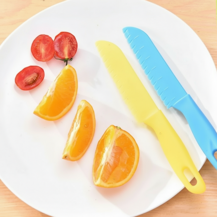 Blue and yellow serrated knives on a plate with orange wedges and tomatoes