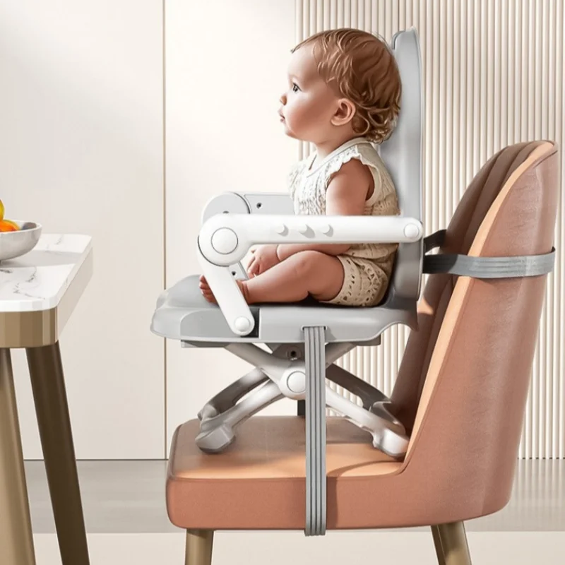 Side view of a child in the gray booster chair at a dining table