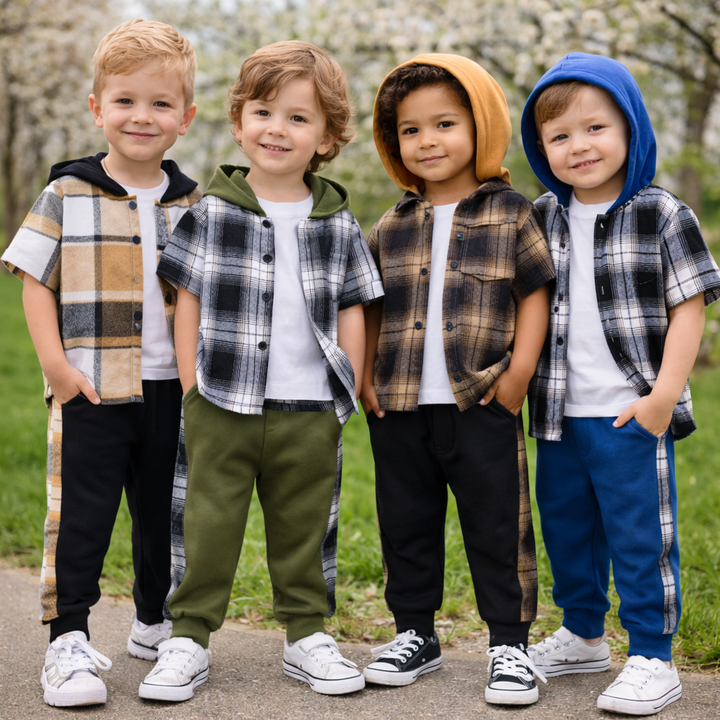 Four boys wearing short-sleeve plaid hooded tops and coordinating pants in a meadow