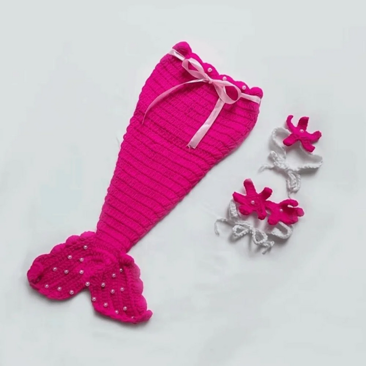 Bright pink knitted mermaid tail with a pale ribbon bow and coordinating starfish accessories