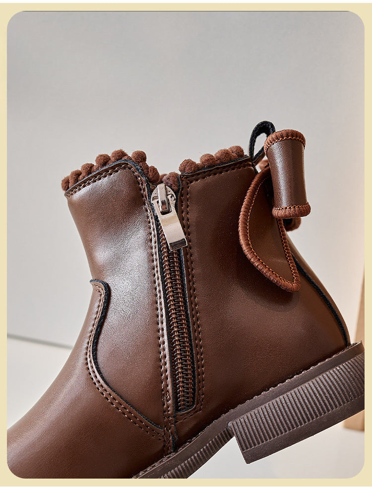 Close-up of the side zipper, back bow, and decorative trim on a brown ankle boot