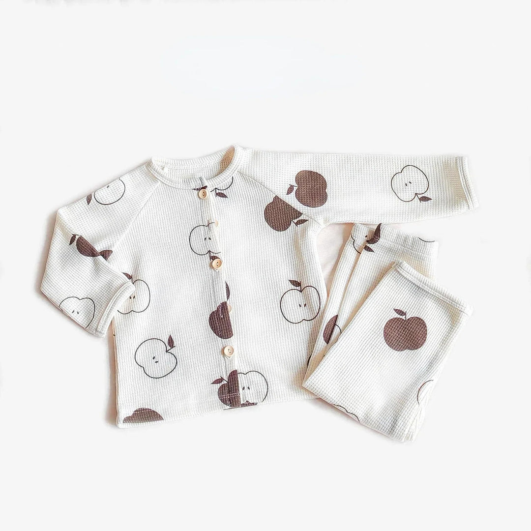 White pajama set with brown and outlined apple prints, long sleeves, and matching pants