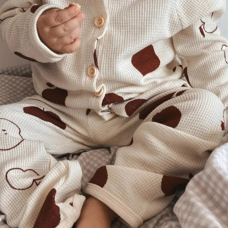 Close-up of textured white cotton pajamas with brown apple prints and front buttons