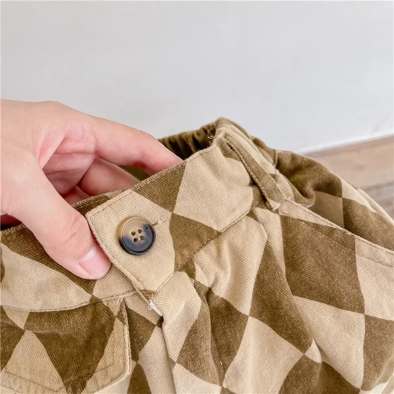 Close-up of the button closure and gathered waistband on brown argyle pants