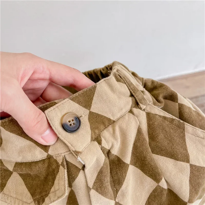 Close-up of the button closure and gathered waistband on brown argyle pants