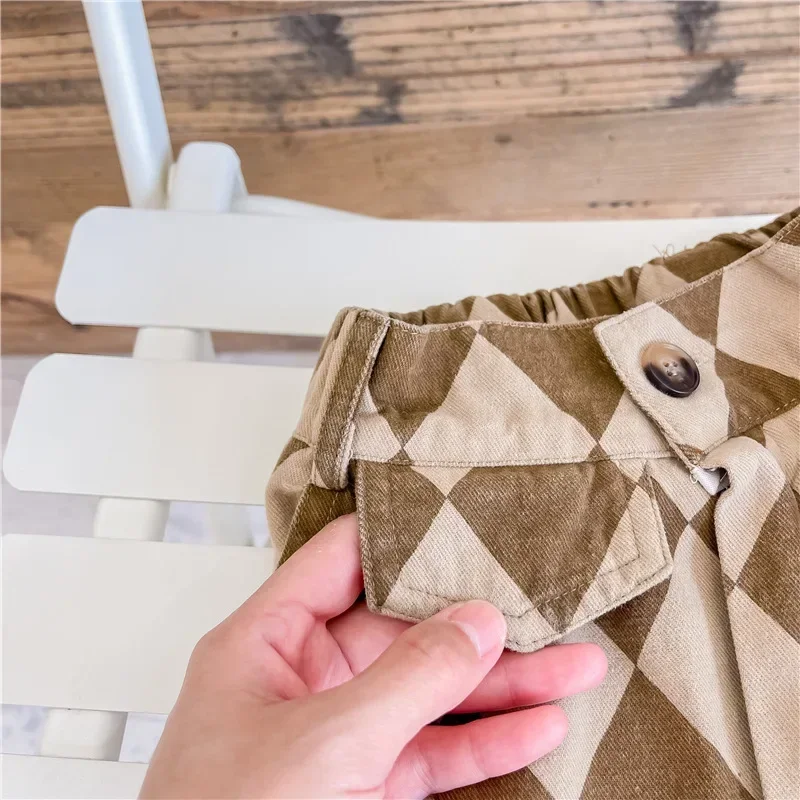 Hand holding the pocket flap on brown and cream argyle pants