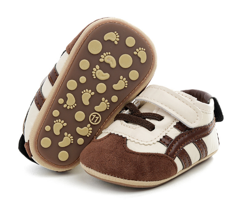 Brown and cream baby sneakers showing footprint-shaped tread and round grip dots