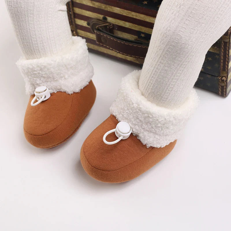 Brown baby winter boots being worn, showing fluffy white cuffs and white toggles