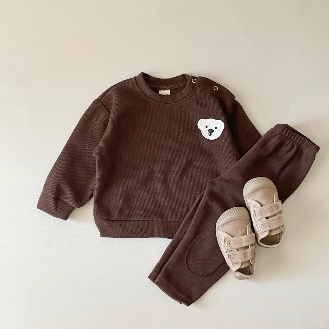 Brown cotton sweater with a white bear detail and matching elastic-waist pants, styled with sandals