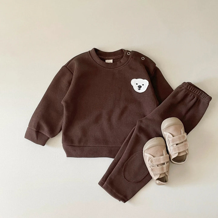 Brown cotton sweater with a white bear detail and matching elastic-waist pants, styled with sandals