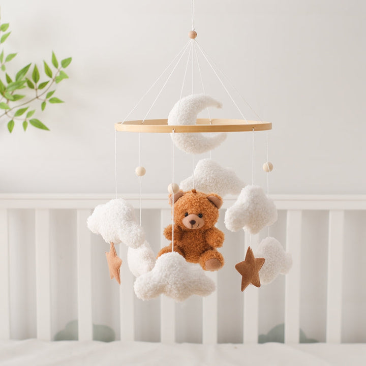 Brown bear baby mobile with white clouds, a crescent moon and stars hanging above a crib
