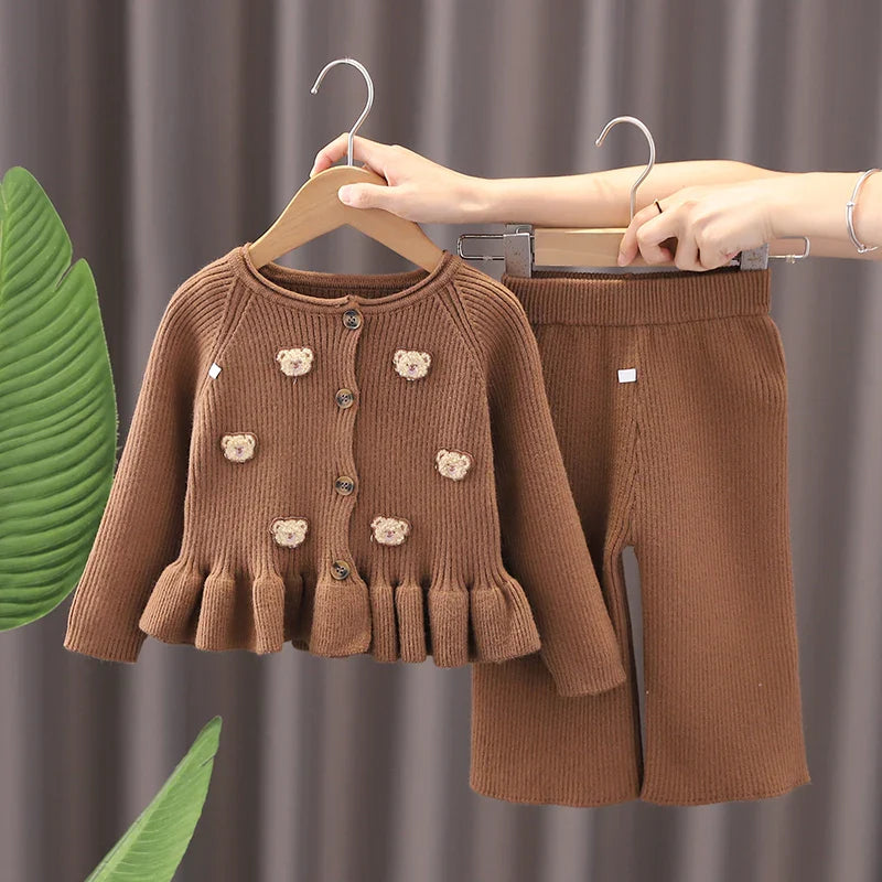 Front view of a brown bear sweater with a ruffled hem and matching pants on hangers