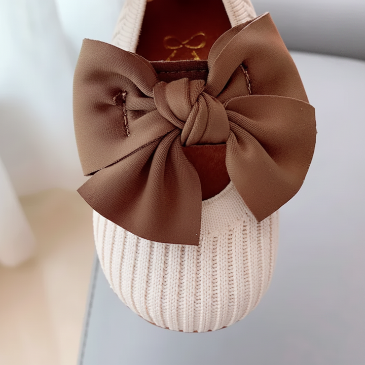 Close-up of a brown butterfly bow on a ribbed white shoe upper