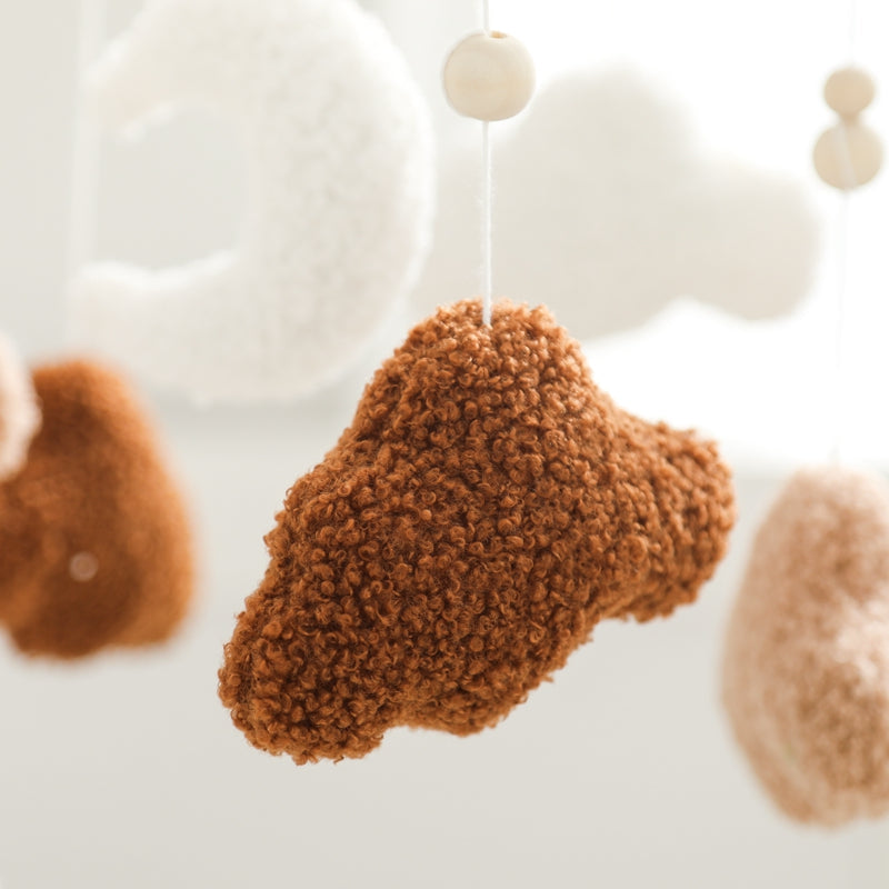 Brown cotton cloud suspended below a wooden bead, with white clouds behind it