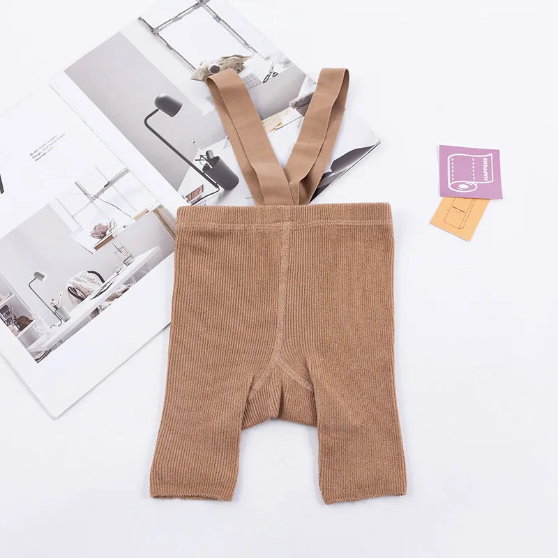 Brown ribbed suspender shorts laid flat with matching shoulder straps.