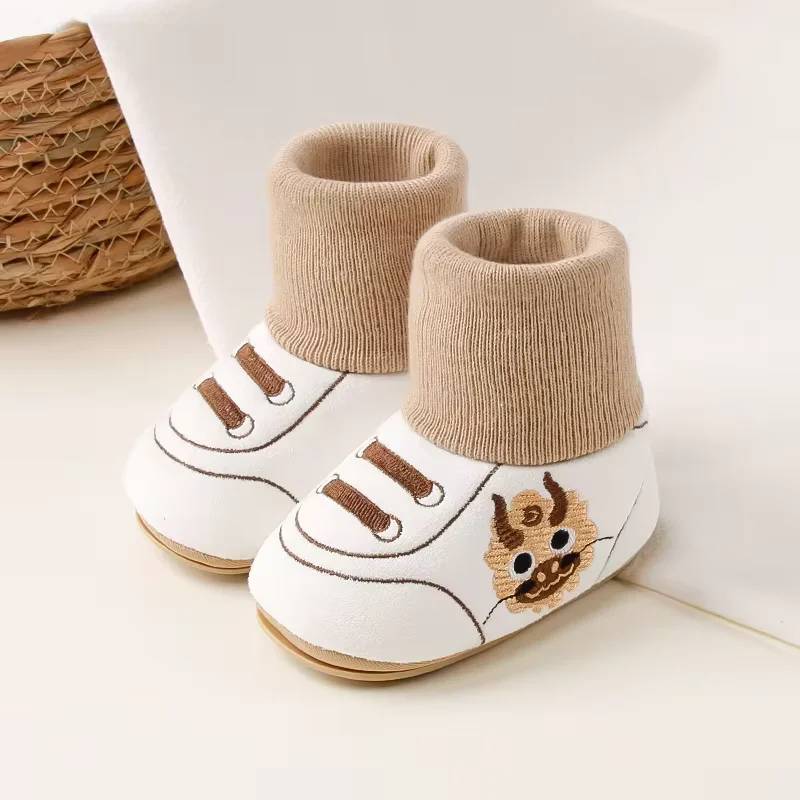 Pair of white baby shoes with brown knit cuffs and animal side motifs.