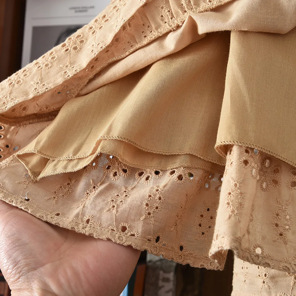 Close-up of the brown dress hem showing eyelet embroidery and a smooth inner layer