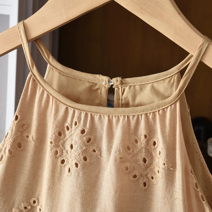 Close-up of the brown dress neckline, thin straps and embroidered floral eyelets