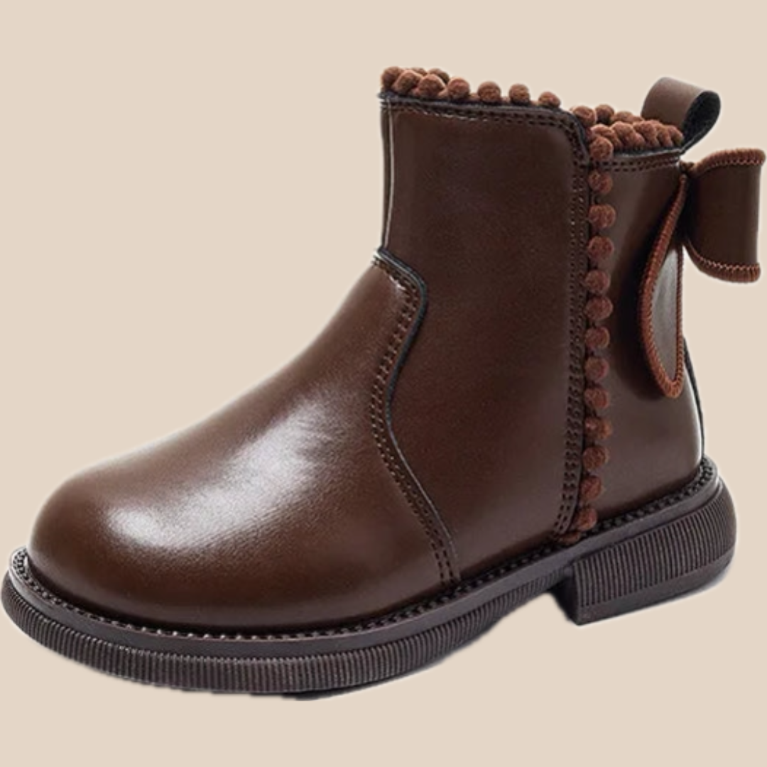 Angled view of a brown faux-leather ankle boot with decorative edging and a back bow