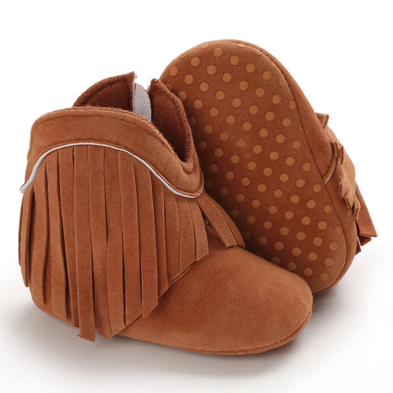 Brown fringe baby boots with one sole turned up to show its dotted pattern