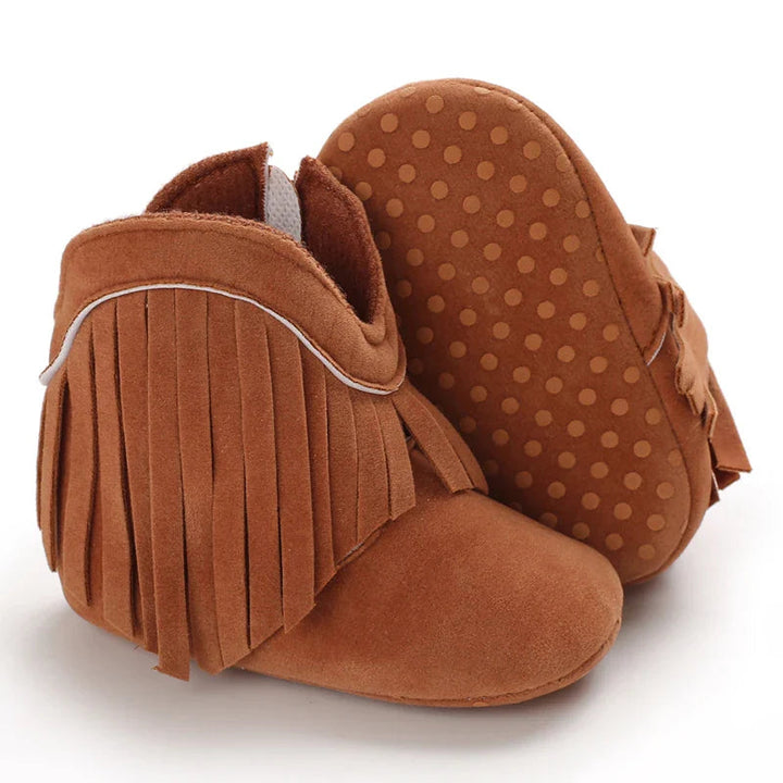 Brown fringe baby boots with one sole turned up to show its dotted pattern