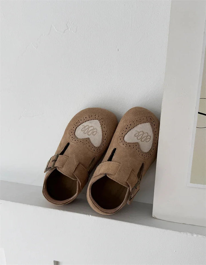 Brown heart-detail shoe pair resting on a white ledge