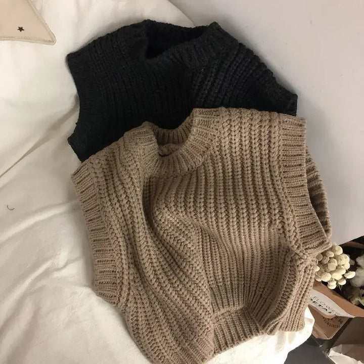 Brown cotton sweater vest laid over a black vest, showing the ribbed hem